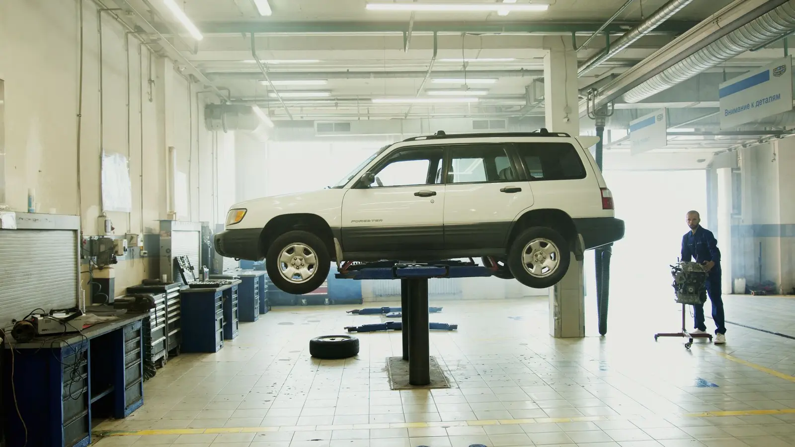 A mechanic working on a car raised on a lift in a bright workshop
